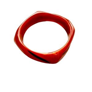 Square resin bangle bracelet in rust color with black marks.